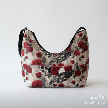Handbag with red floral and black skull design and a black handle on a light gray background