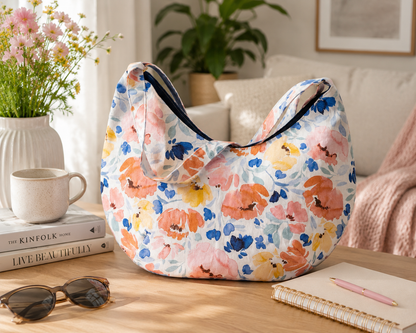 Floral-patterned bag on a table with books, sunglasses, and a notebook in a home setting.