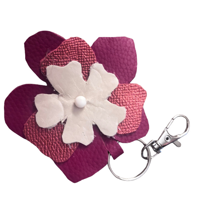 A flower-shaped leather keychain accessory featuring layered magenta and pink textured petals with a central white flower and a silver metal clasp.