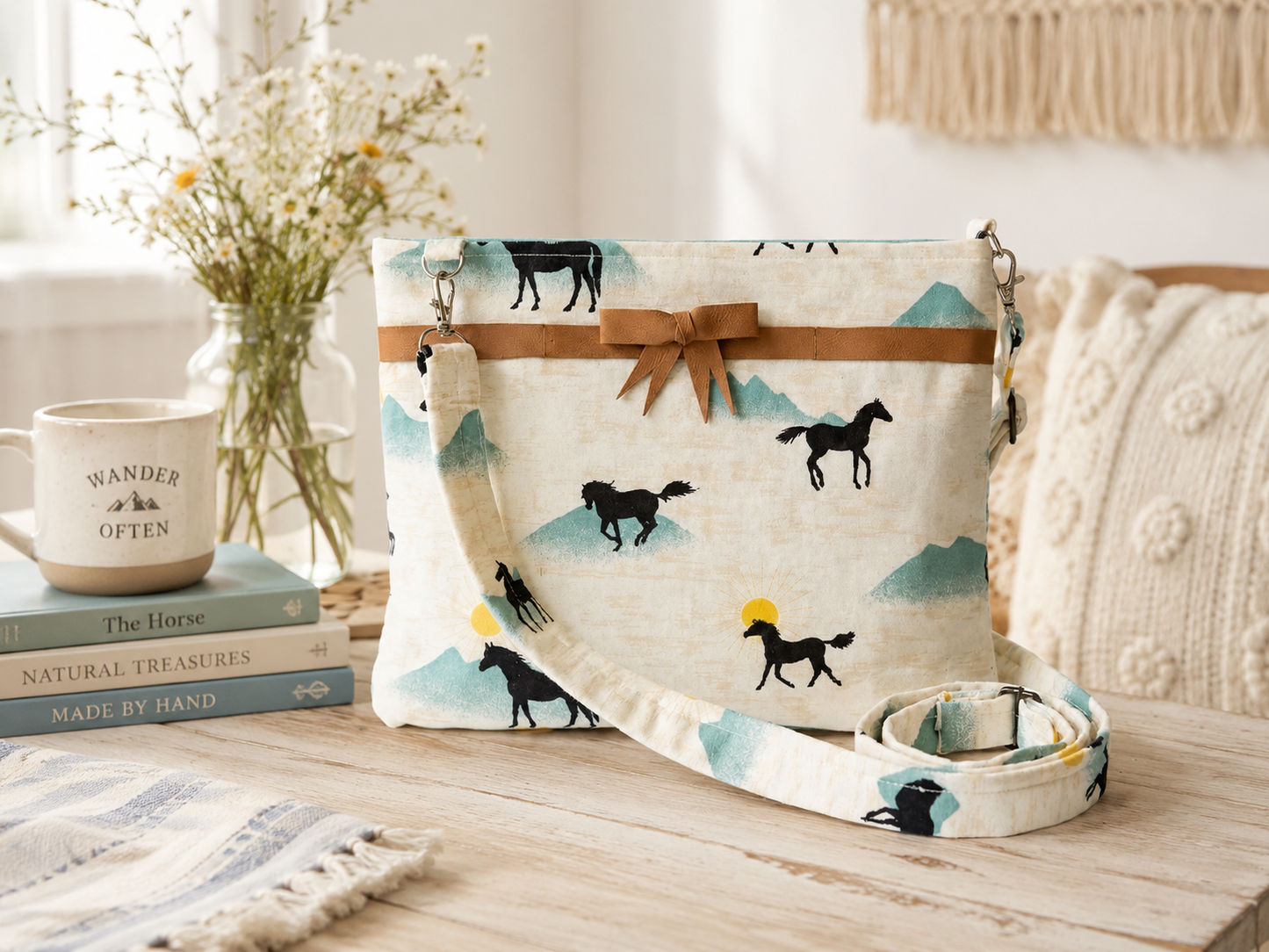 Handbag with horse pattern on a wooden surface with books and decor items.