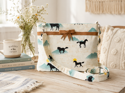 Handbag with horse pattern on a wooden surface with books and decor items.