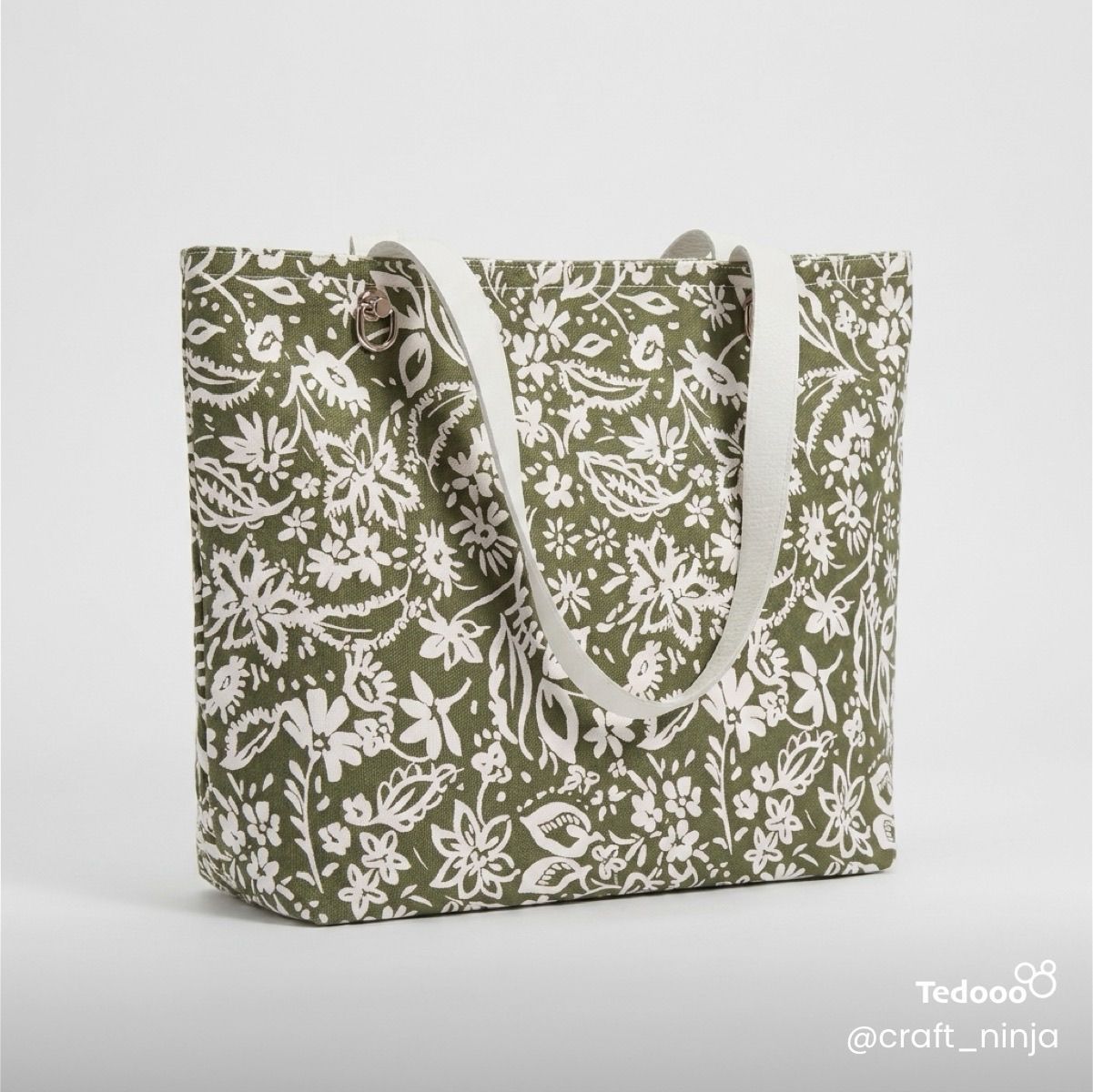 Sage green botanical patterned tote bag with white leathers handles.
