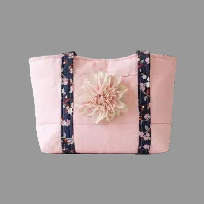 Pink tote bag with navy blue floral straps and a large light pink daisy flower on the front.